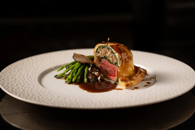 Sliced beef Wellington with asparagus and jus.