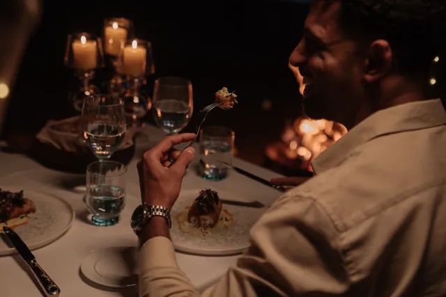 A guest smiles over a candlelit dinner.