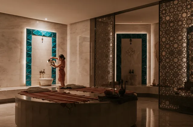 A marble hammam with turquoise tiles and carved screens.