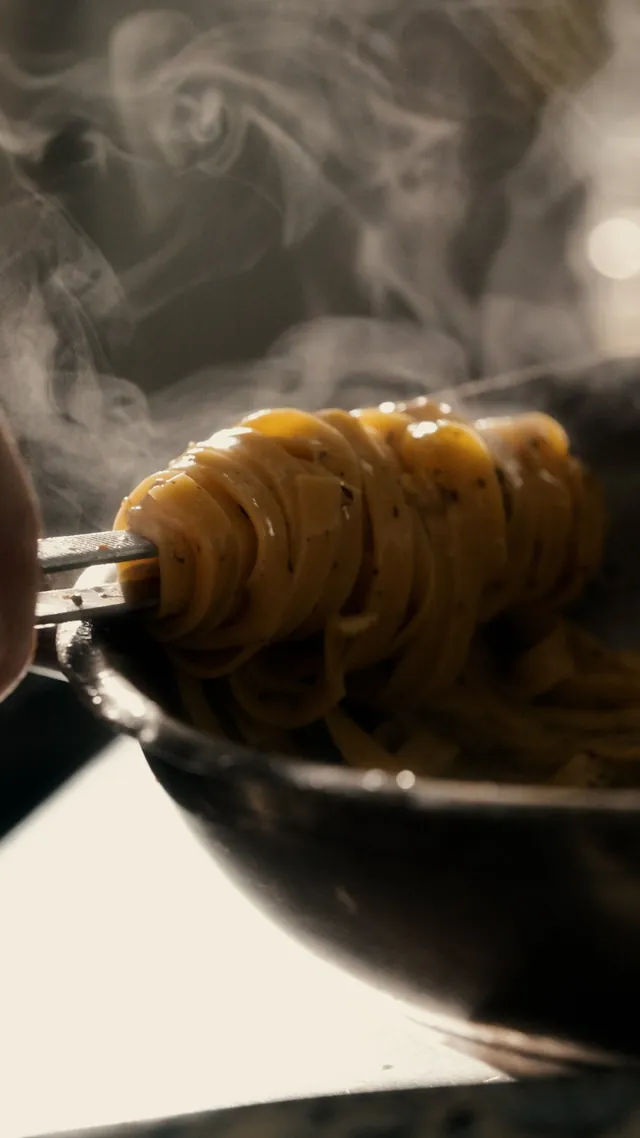 Steam rises from a forkful of fresh pasta.