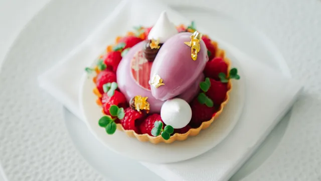 A raspberry tart finished with gold leaf, meringue and micro herbs.