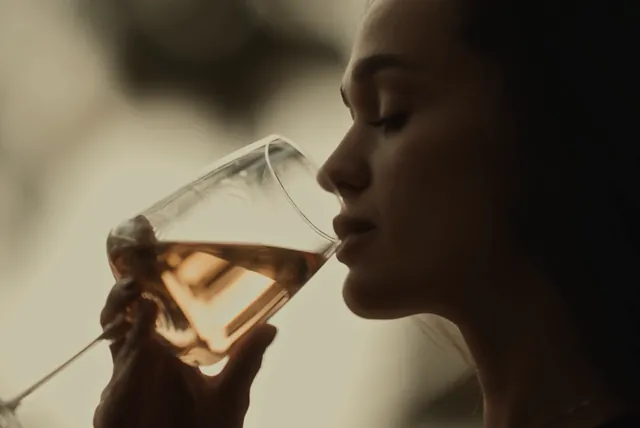 A woman closes her eyes as she tastes a glass of rosé.