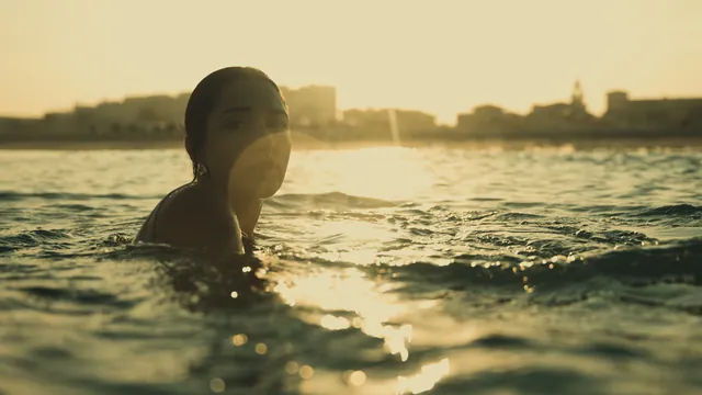 A swimmer in the sea at sunset with the skyline on the horizon.
